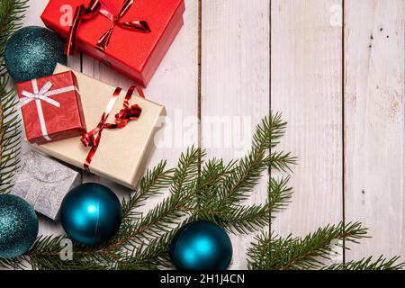 Christmas flat lay with presents, blue tree ornaments and pine branches on a white wooden background. Copy space on the right. Stock Photo