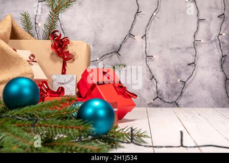 Christmas concept. Jute sack with many Christmas gifts. Red, brown and silver packages with red ribbons on a white wooden board. Christmas decorations Stock Photo