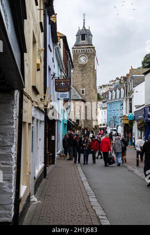 Out of season visitors in Fore Street with the prominent clock tower, Looe, Cornwall. A working fishing harbour popular with holidaymakers. Stock Photo