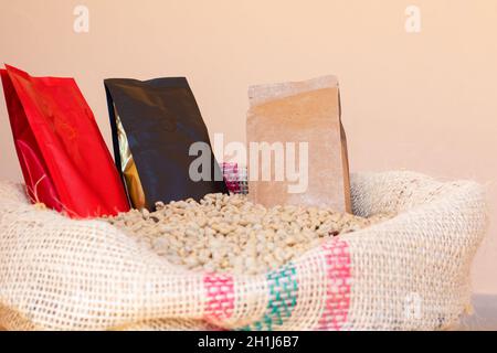 Three coffee packaging bags. Paper bags for coffee on sack full of coffee beans. Stock Photo