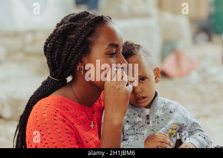 Inticho, Tigray Region, Ethiopia - April 28, 2019: Ethiopian beautiful local women with son looking to visitors on the street of Inticho city, Ethiopi Stock Photo