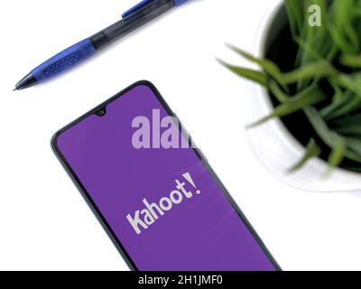 Lod, Israel - July 8, 2020: Modern minimalist office workspace with black mobile smartphone with Kahoot! app launch screen with logo on a white backgr Stock Photo