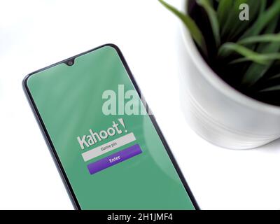 Lod, Israel - July 8, 2020: Modern minimalist office workspace with black mobile smartphone with Kahoot! app launch screen with logo on a white backgr Stock Photo