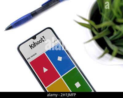 Lod, Israel - July 8, 2020: Modern minimalist office workspace with black mobile smartphone with Kahoot! app launch screen with logo on a white backgr Stock Photo