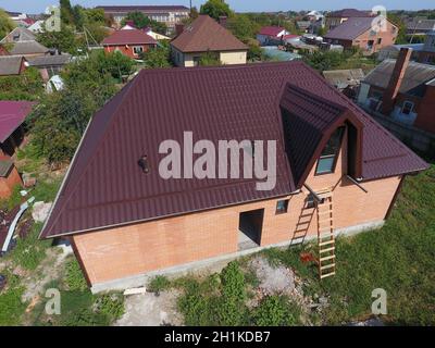 The roof of corrugated sheet. Roofing of metal profile wavy shape. A view from above on the roof of the house. Stock Photo