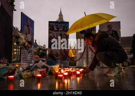 A man holding an umbrella leaves a candle at a memorial outside the Parliament for Sir David Amess.Anglo-Iranian community members held a memorial service and vigil outside the Parliament to pay tribute to the murdered MP Sir David Amess. (Photo by Tejas Sandhu / SOPA Images/Sipa USA)