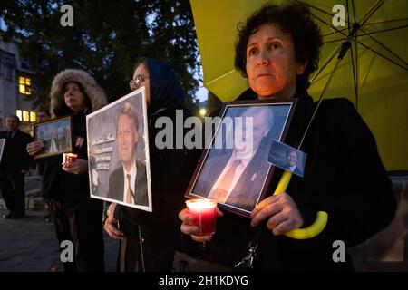 London, UK. 18th Oct, 2021. Supporters of the National Council of Resistance of Iran (NCRI) hold up pictures and candles to pay tribute to Sir David Amess who was fatally stabbed several times last week while holding a constituency surgery in Leigh on Sea, Essex.Anglo-Iranian community members held a memorial service and vigil outside the Parliament to pay tribute to the murdered MP Sir David Amess. (Photo by Tejas Sandhu/SOPA Images/Sipa USA) Credit: Sipa USA/Alamy Live News Stock Photo