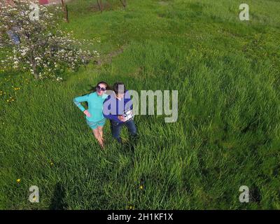 A man and a woman are photographed from a drone on a green clearing Stock Photo
