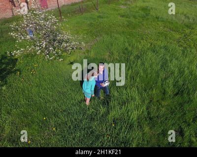 A man and a woman are photographed from a drone on a green clearing Stock Photo