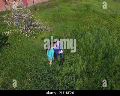 A man and a woman are photographed from a drone on a green clearing Stock Photo