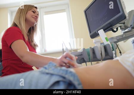Doctor conducts ultrasound examination of woman in clinic closeup Stock Photo