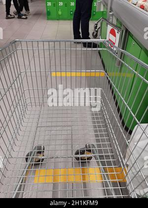 Social distance. Marking with yellow lines in a supermarket store to maintain distance under quarantine. Distance markings, signs on the floor in a dr Stock Photo