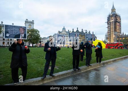 London, UK. 18th Oct, 2021. Supporters of the National Council of Resistance of Iran (NCRI) hold up pictures and candles at a memorial for Sir David Amess who was fatally stabbed several times last week whilst holding a constituency surgery in Leigh on Sea, Essex.Anglo-Iranian community members held a memorial service and vigil outside the Parliament to pay tribute to the murdered MP Sir David Amess. Credit: SOPA Images Limited/Alamy Live News Stock Photo