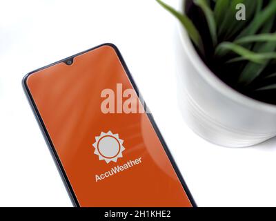 Lod, Israel - July 8, 2020: Modern minimalist office workspace with black mobile smartphone with AccuWeather app launch screen with logo on white back Stock Photo