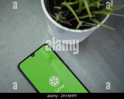 Lod, Israel - July 8, 2020: Modern minimalist office workspace with black mobile smartphone with Lime app launch screen with logo on marble background Stock Photo