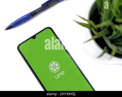 Lod, Israel - July 8, 2020: Modern minimalist office workspace with black mobile smartphone with Lime app launch screen with logo on white background. Stock Photo