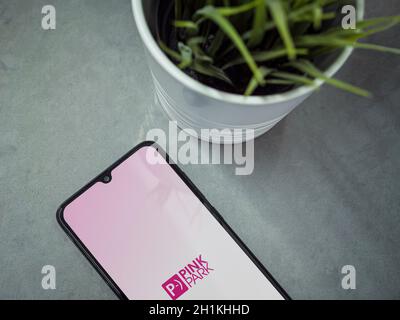 Lod, Israel - July 8, 2020: Modern minimalist office workspace with black mobile smartphone with Pink Park app launch screen with logo on marble backg Stock Photo