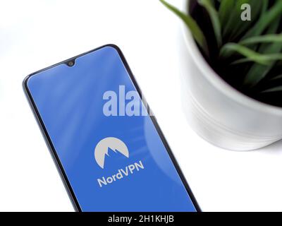 Lod, Israel - July 8, 2020: Modern minimalist office workspace with black mobile smartphone with NordVPN app launch screen with logo on white backgrou Stock Photo