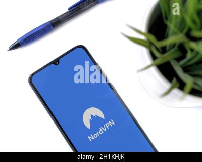 Lod, Israel - July 8, 2020: Modern minimalist office workspace with black mobile smartphone with NordVPN app launch screen with logo on white backgrou Stock Photo