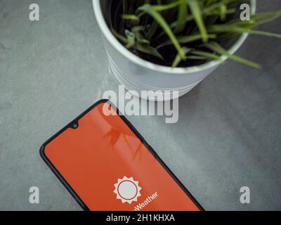 Lod, Israel - July 8, 2020: Modern minimalist office workspace with black mobile smartphone with AccuWeather app launch screen with logo on marble bac Stock Photo