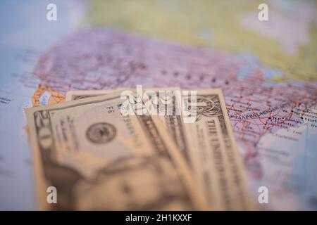 Close up picture of blurry banknotes of one, two, and twenty dollars below a purple map of the United States of America with its main routes marked in Stock Photo