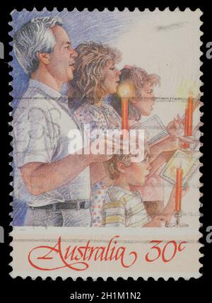 Christmas stamp printed in Australia shows family singing with candles, circa 1988 Stock Photo