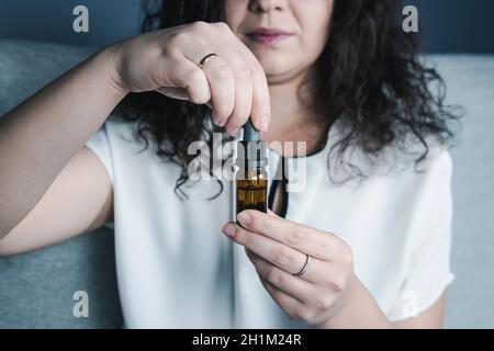 Close-up of females hand holding bottle with cbd oil drops. Concepts of alternative medicine and herbs Stock Photo