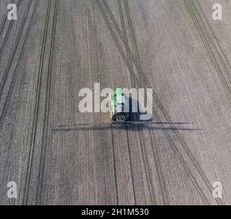 Tractor with hinged system of spraying pesticides. Fertilizing with a tractor, in the form of an aerosol, on the field of winter wheat Stock Photo