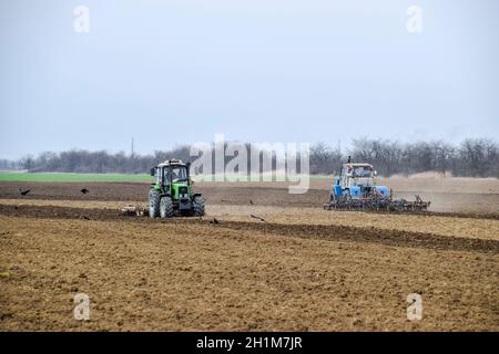 Lush and loosen the soil on the field before sowing. The tractor plows a field with a plow. Stock Photo