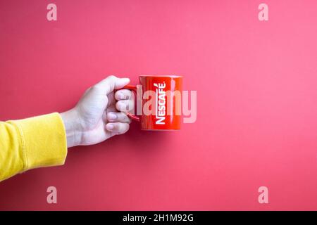 Kuala Lumpur, Malaysia - November 12, 2020 : Hand holding Nescafe Mug on red background Stock Photo