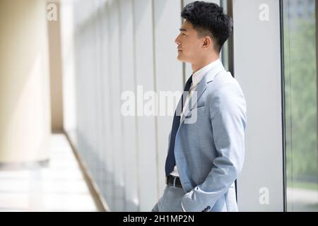 Businessman standing by the window and thinking Stock Photo
