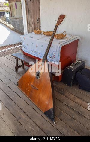 Balalaika-contrabass under a canopy in a cottage. Bass balalaika rare instrument. Stock Photo
