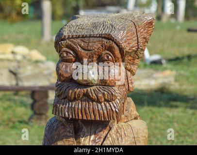 The face of a bearded old man carved out of logs. Wooden idol. Stock Photo