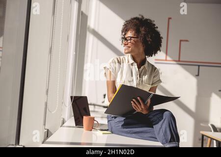 Pretty multiethnic lady sitting at work desk in the office Stock Photo