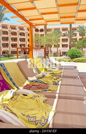 Empty deck chairs with towels on tropical resort beach. Chaise longues near five stars hotel. Holidays concept. Place for relax near seaside Stock Photo