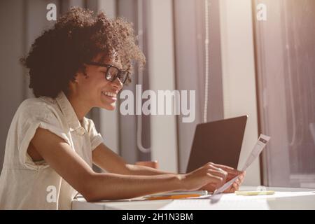 Smiling Afro American woman holding paper in the office Stock Photo