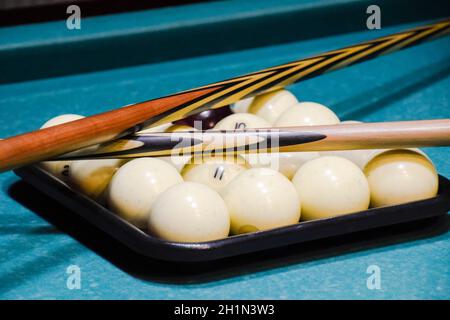 Billiards, billiard table, balls and cue. Balls in the tray and two cues on the balls. Stock Photo