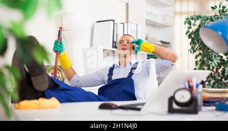 Relaxed worker of office cleaning service talking on phone during break Stock Photo