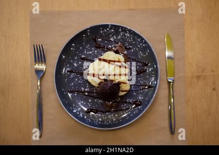 Delicious sweet banana split ice cream dessert with garnishment of chocolate syrup, and peppermint leaf on top in bowl on table Stock Photo