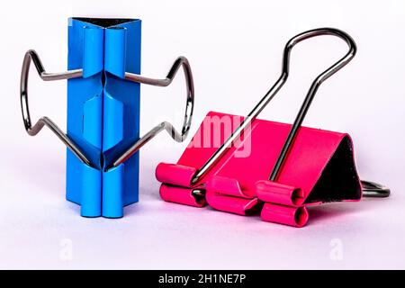 Two pink and blue metallic paper clips, isolated on a white background, for a cheerful office, work, school and business concept Stock Photo