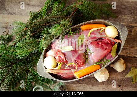 Roasted wild rabbit haunch with stewed vegetables in pan garnished with fresh herbs, flat lay Stock Photo