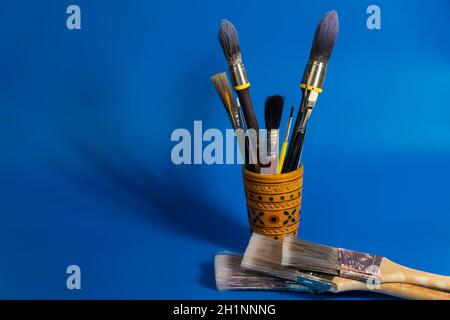 Brushes for painting in a wooden pencil case on an old canvas painted with blue background Stock Photo