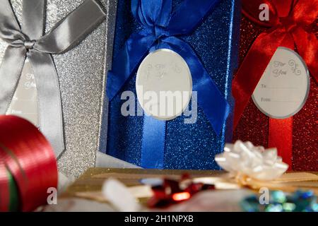 Silver, blue, red, and gold gift boxes next to wrapping ribbon Stock Photo