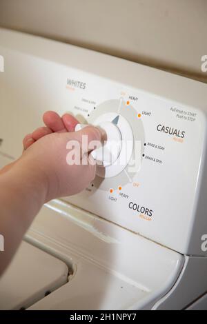 Woman turning a knob on a laundry washing machine Stock Photo