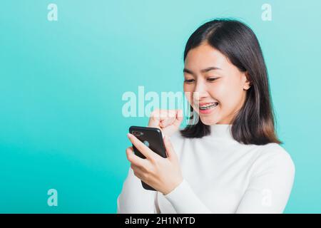 Asian woman smile holding smartphone she happy and surprised after received message, female excited cheerful her reading mobile phone some social medi Stock Photo