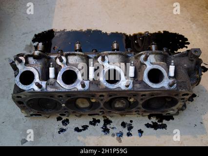 The head of the block of cylinders. The head of the block of cylinders removed from the engine for repair. Parts in engine oil. Car engine repair in t Stock Photo