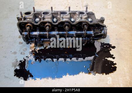 The head of the block of cylinders. The head of the block of cylinders removed from the engine for repair. Parts in engine oil. Car engine repair in t Stock Photo