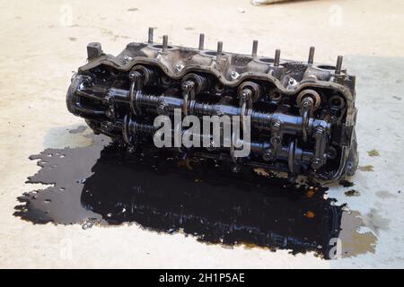 The head of the block of cylinders. The head of the block of cylinders removed from the engine for repair. Parts in engine oil. Car engine repair in t Stock Photo