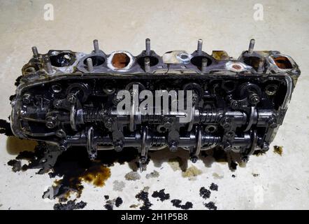 The head of the block of cylinders. The head of the block of cylinders removed from the engine for repair. Parts in engine oil. Car engine repair in t Stock Photo