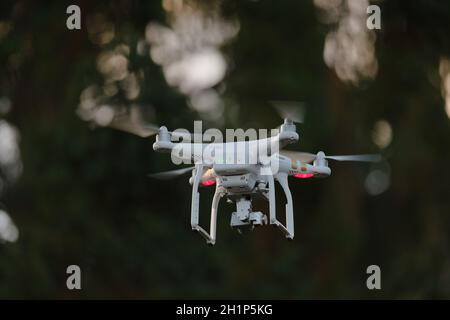 22 - Rear view of white quadcopter camera drone with gimbal underneath. Battery indicator lights show battery status on the back side of the aircraft Stock Photo